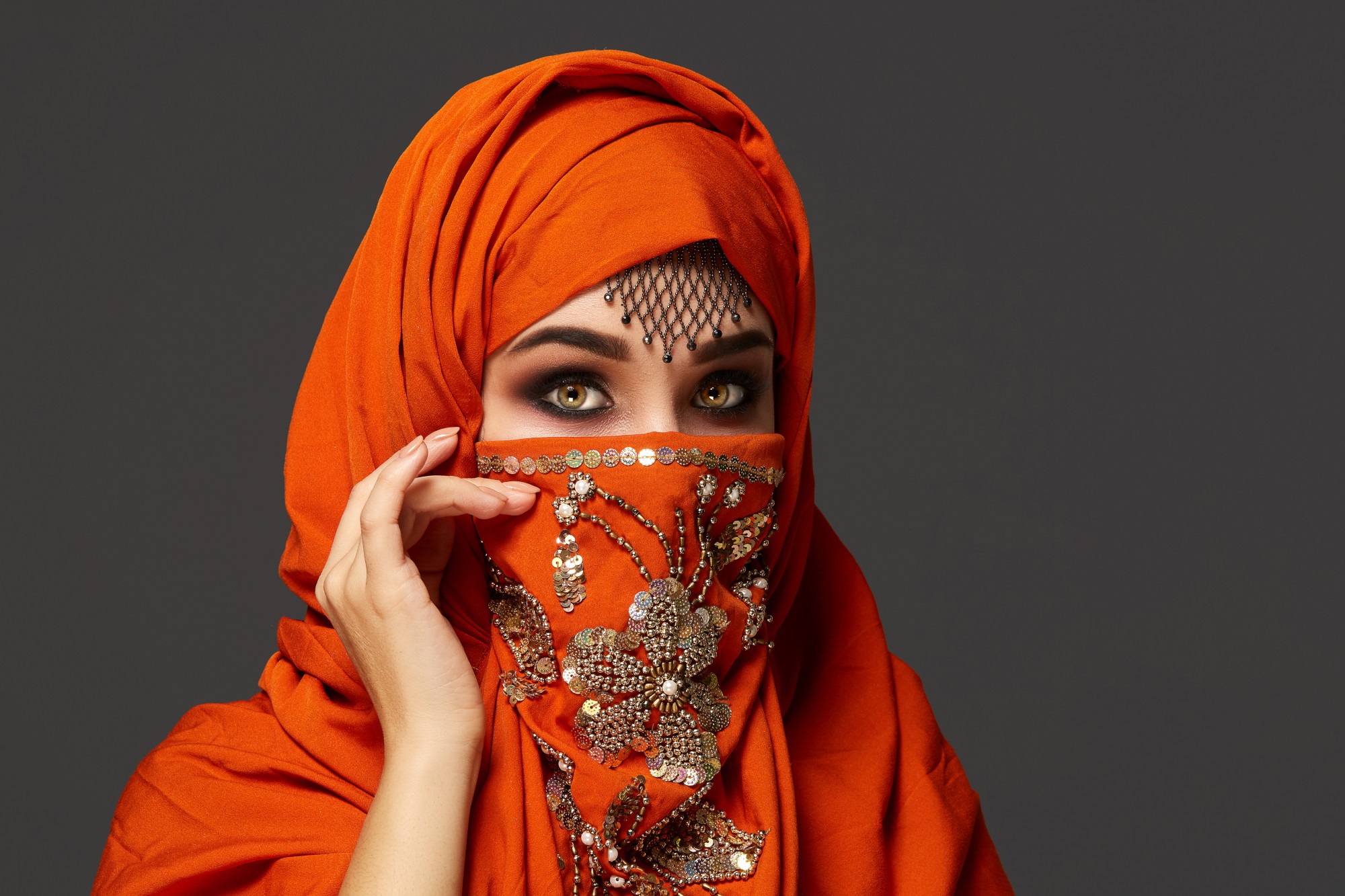 close-up-portrait-good-looking-young-woman-with-beautiful-smoky-eyes-fine-jewelry-forehead-wearing-terracotta-hijab-decorated-with-sequins-she-is-posing-sideways-looking-t